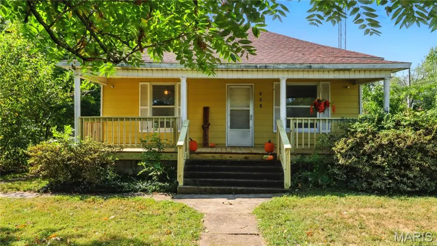 Bungalow-style house with covered porch, a shingled roof, and a front lawn