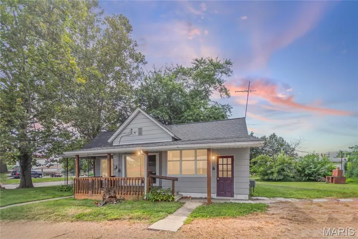 View of front of property with covered porch, a front yard, and a shingled roof