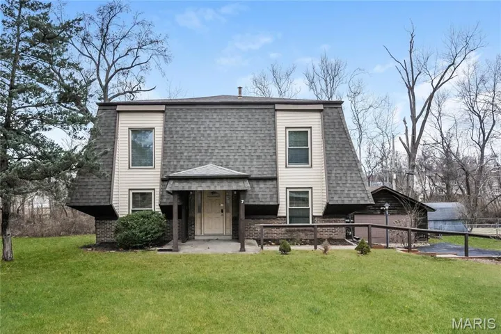 View of front facade featuring brick siding, a front lawn, and roof with shingles