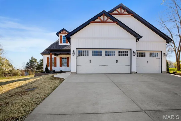 Modern inspired farmhouse with a porch, concrete driveway, an attached garage, and a shingled roof