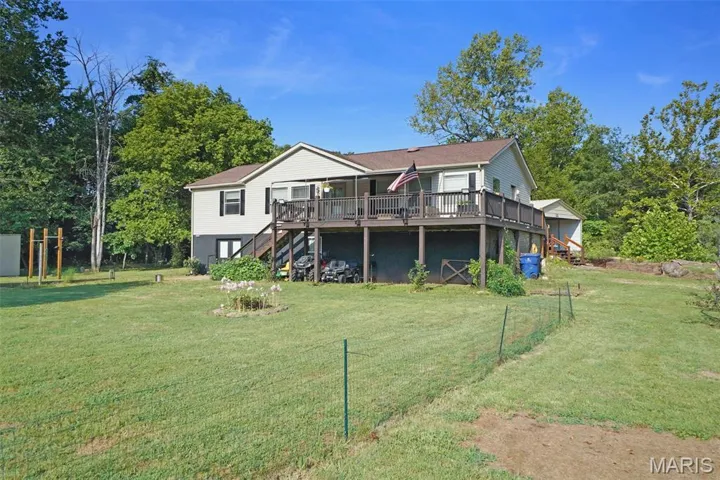 Back of house with stairway, a wooden deck, and a lawn