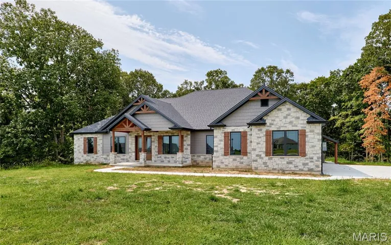 Craftsman-style home featuring a front yard, covered porch, stone siding, and roof with shingles