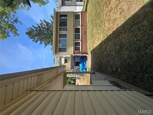 View of home's exterior featuring brick siding, a patio, a lawn, and a sunroom