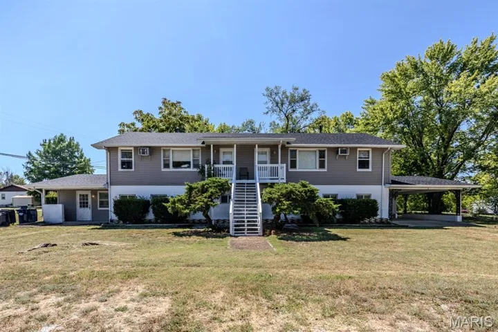 View of front facade featuring stairway, a front lawn, an attached carport, and covered porch