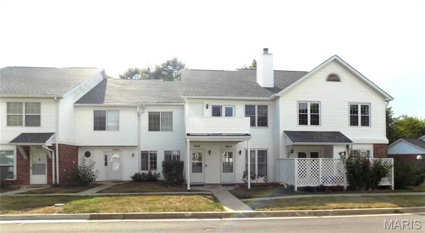 View of front facade with a chimney, roof with shingles, a front lawn, and brick siding