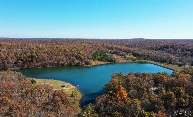 View of property location featuring a forest and a nearby body of water