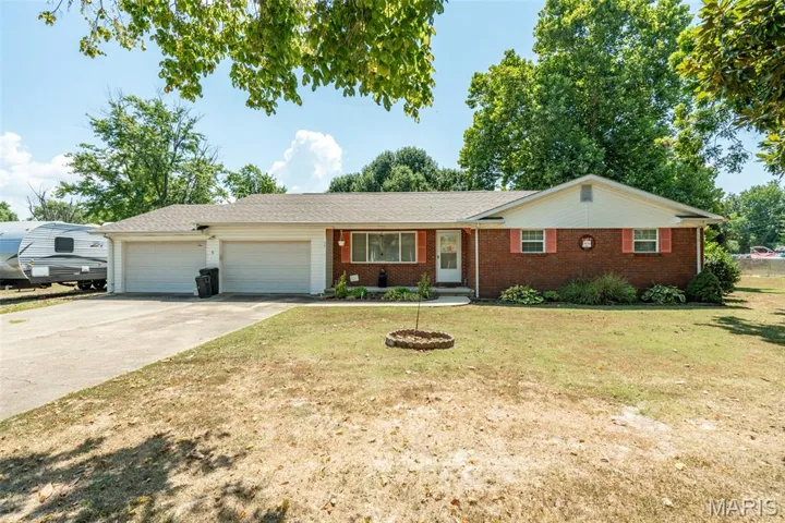 Ranch-style home featuring an attached garage, brick siding, driveway, and a front lawn