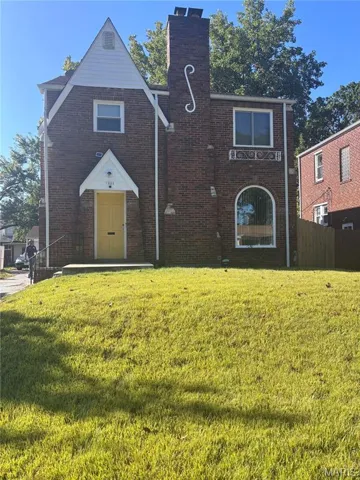 View of front of home with brick siding and a chimney