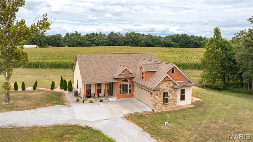 Craftsman-style house with driveway, stone siding, covered porch, a garage, and a front yard