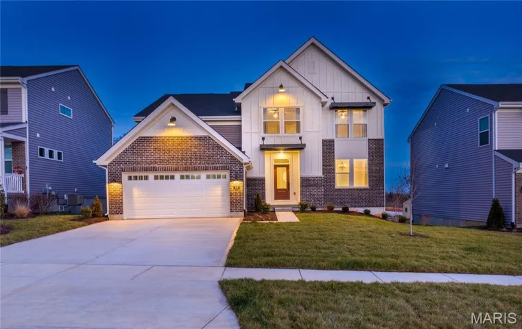 Modern farmhouse featuring brick siding, board and batten siding, driveway, a front yard, and an attached garage