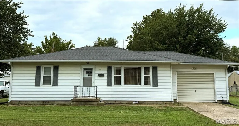 Ranch-style house featuring a front yard, a garage, a shingled roof, and driveway