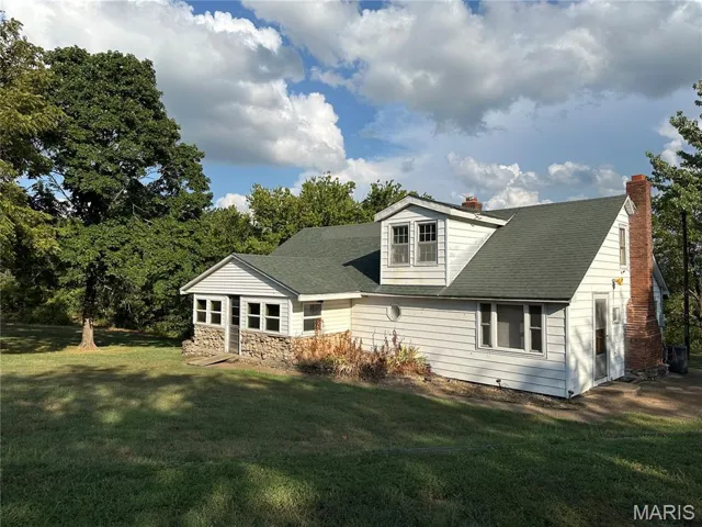 Back of property with a yard, roof with shingles, and a chimney