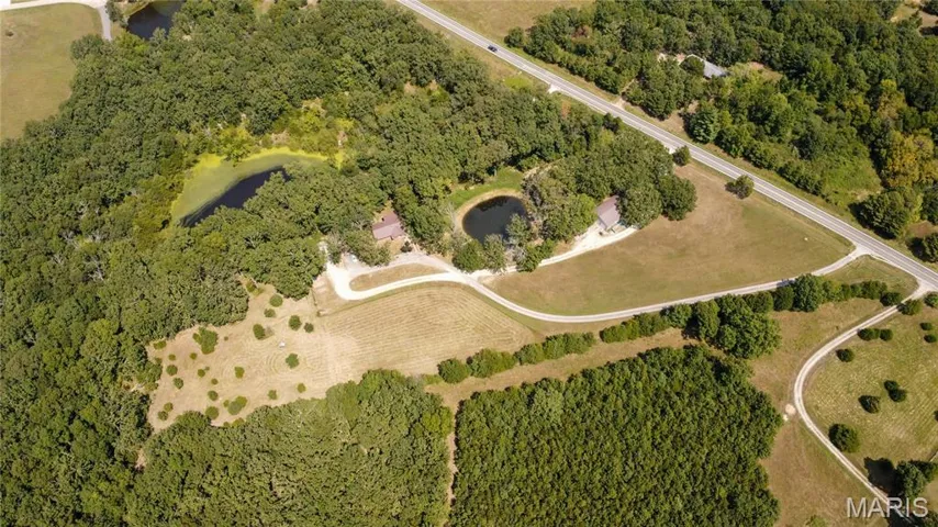 Aerial view of property and surrounding area with a forest
