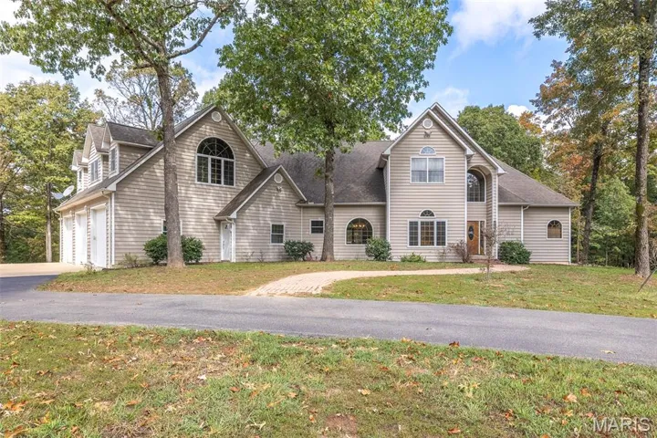 View of front of property featuring a garage, a front lawn, driveway, and a shingled roof