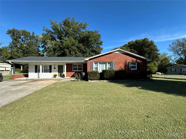 Ranch-style home with a front lawn, brick siding and a freshly painted door.