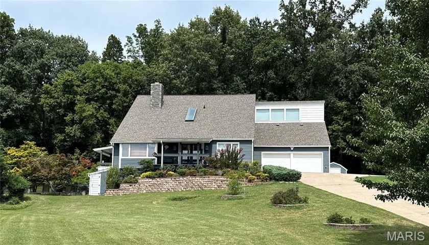 View of front of property featuring a garage, a front yard, driveway, and a shingled roof