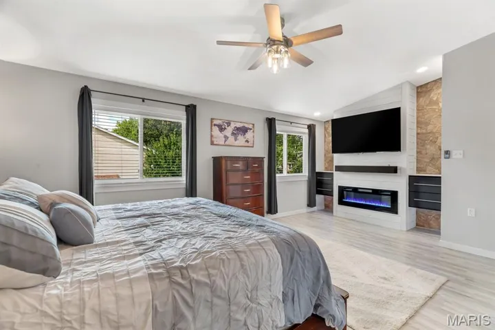 Bedroom with light wood-style flooring, lofted ceiling, a fireplace, ceiling fan, and recessed lighting