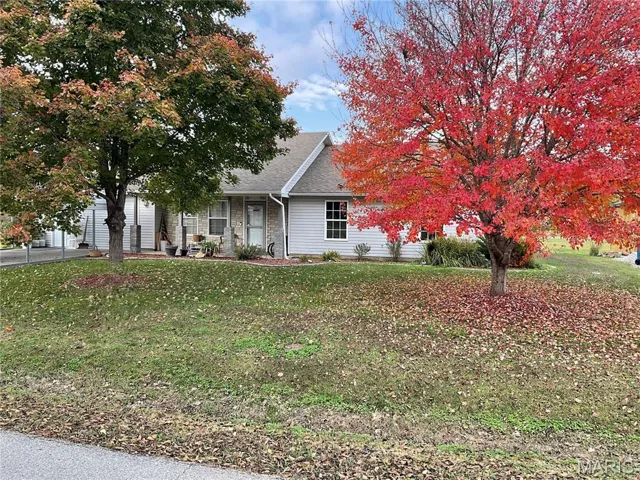 Obstructed view of property featuring a shingled roof, a front yard, brick siding, and a garage