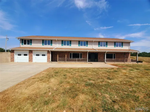 Traditional-style home with driveway, brick siding, a garage, and a front yard