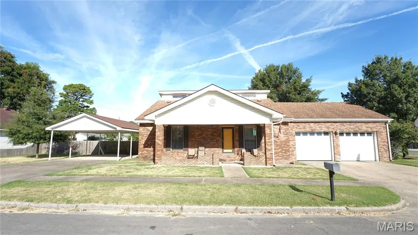 View of front of home featuring covered porch, brick siding, driveway, and roof with shingles