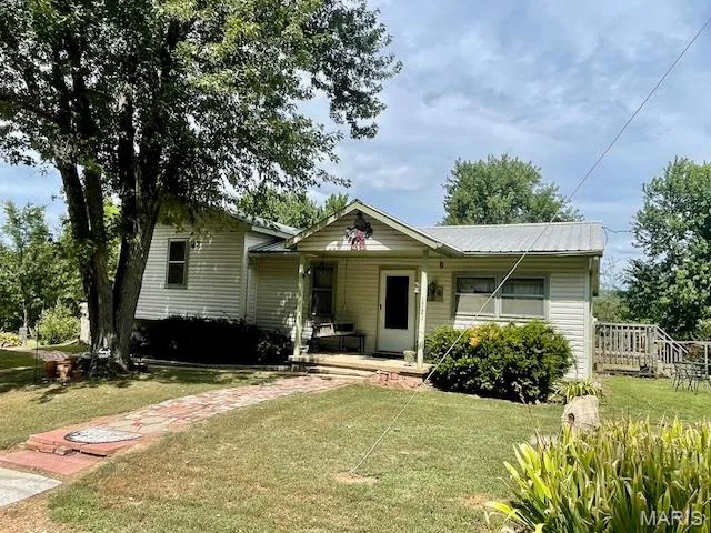 View of front facade featuring a front yard, a porch, and a metal roof
