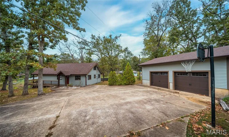 View of property exterior with a garage, a shingled roof, and driveway