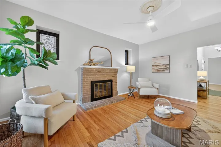 Living area featuring a fireplace, wood finished floors, and ceiling fan