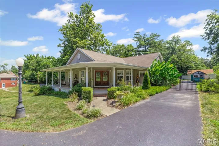 Country-style home with a large porch, asphalt driveway, a front lawn, and roof with shingles