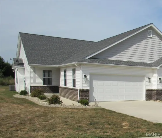 View of home's exterior with brick siding, a garage, driveway, and roof with shingles
