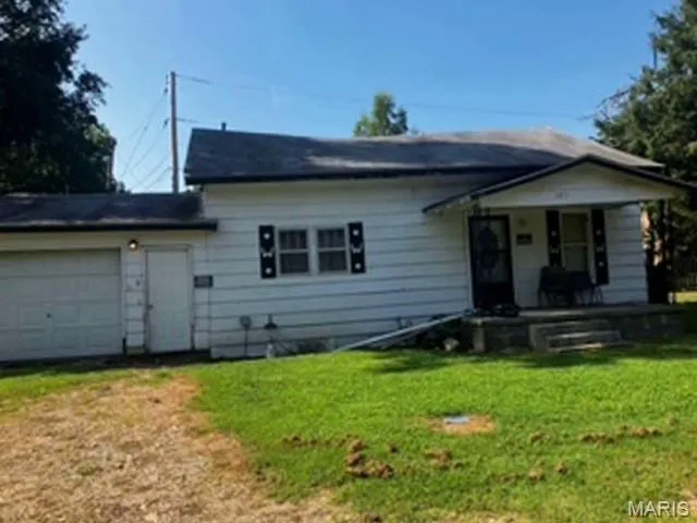 View of front of property featuring an attached garage, a front lawn, and driveway