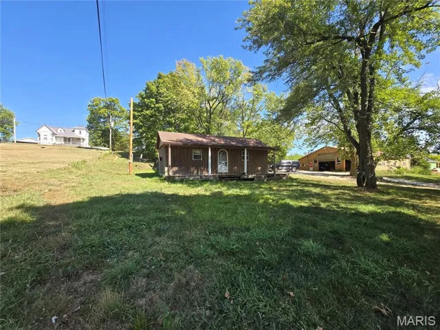 View of grassy yard featuring covered porch and an outdoor structure