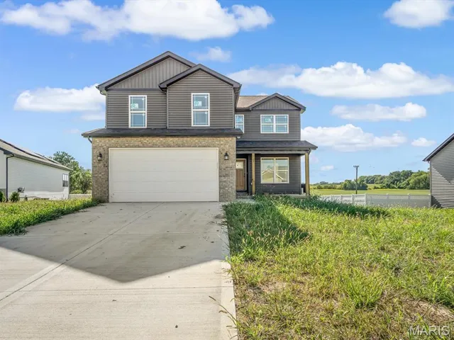 View of front facade featuring an attached garage, concrete driveway, and brick siding