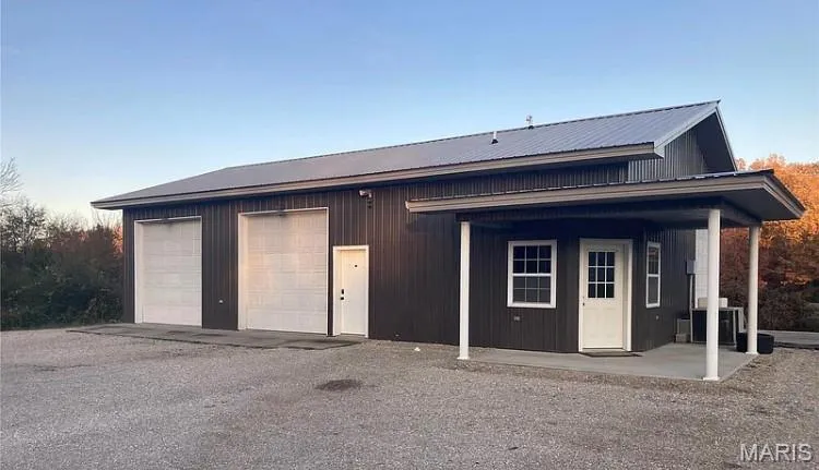 Front of shop with a porch, a garage, and a metal roof