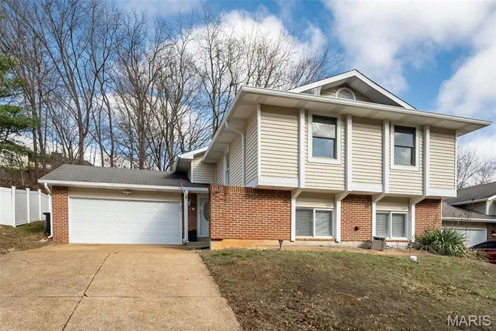 View of front of home with brick siding, concrete driveway, and an attached garage