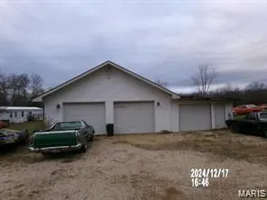 View of side of home with an outdoor structure and dirt driveway