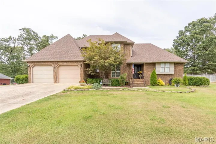 Traditional-style house featuring brick siding, a shingled roof, driveway, and an attached garage
