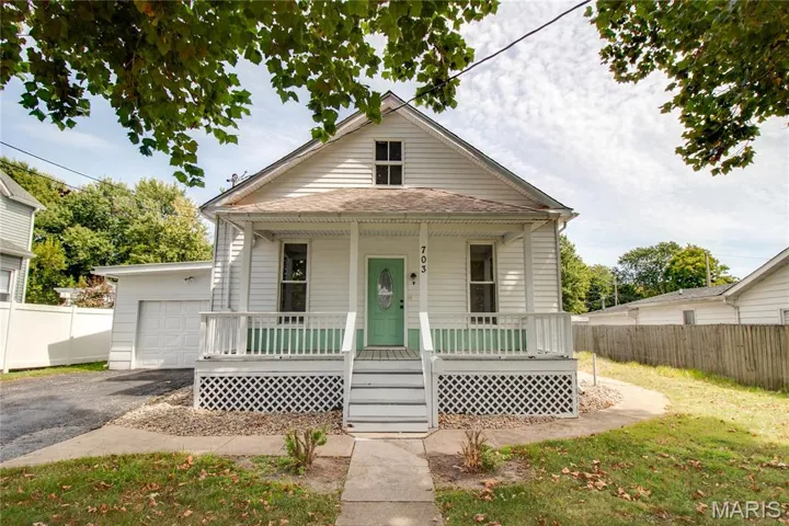 View of front of property featuring a porch, a garage, and asphalt driveway