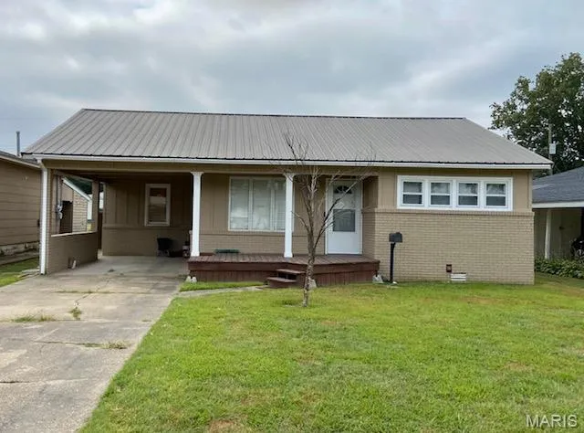 View of front of house featuring brick siding, a porch, a carport, a front lawn, and a metal roof