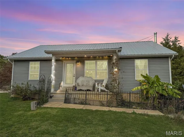 View of front of house with a fenced front yard, a metal roof, and covered porch