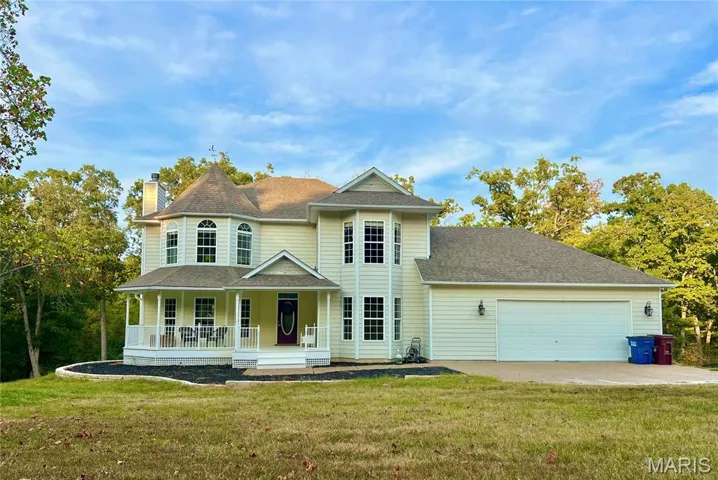 Victorian home with covered porch, a front yard, a chimney, a shingled roof, and concrete driveway