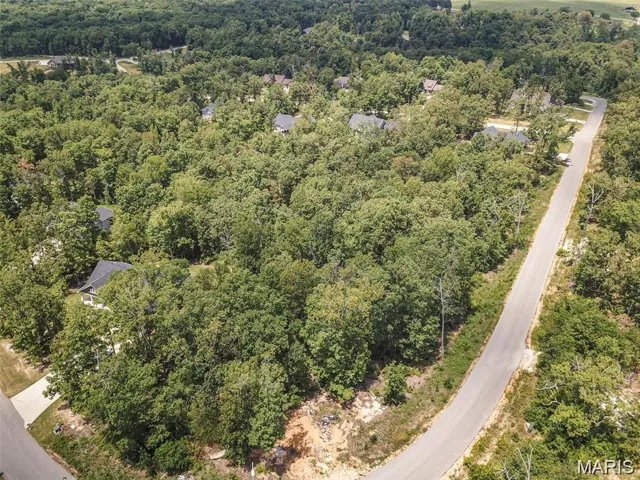 Aerial view of property and surrounding area featuring a forest
