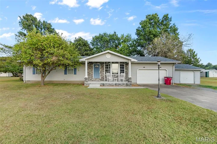 Ranch-style house with a front lawn, concrete driveway, a garage, and a porch