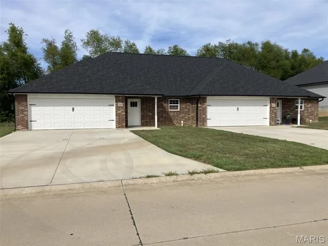 View of front of home with roof with shingles, brick siding, concrete driveway, and a front yard