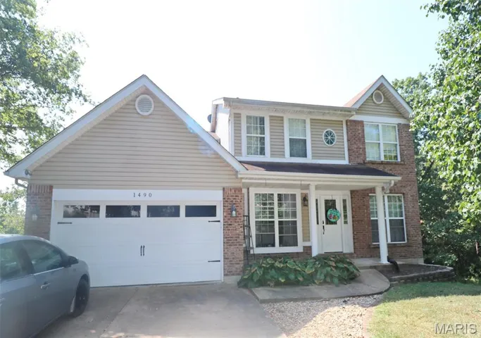 View of front of house featuring a porch, brick siding, concrete driveway, and an attached garage
