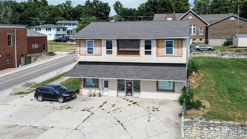 View of front of home with a shingled roof, stucco siding, and a balcony