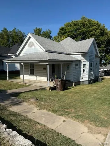 View of front facade with a shingled roof, a porch, and a front yard