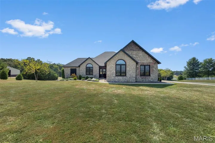 French country style house featuring stone siding and a front lawn
