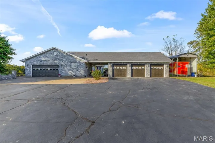 Ranch-style house featuring asphalt driveway, a garage, and stone siding