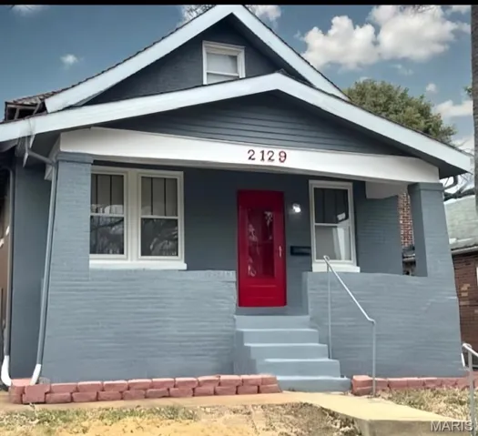 View of front facade featuring covered porch and brick siding