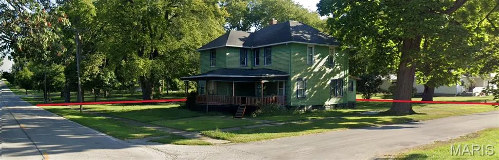 Victorian-style house with a front lawn, covered porch, and a chimney